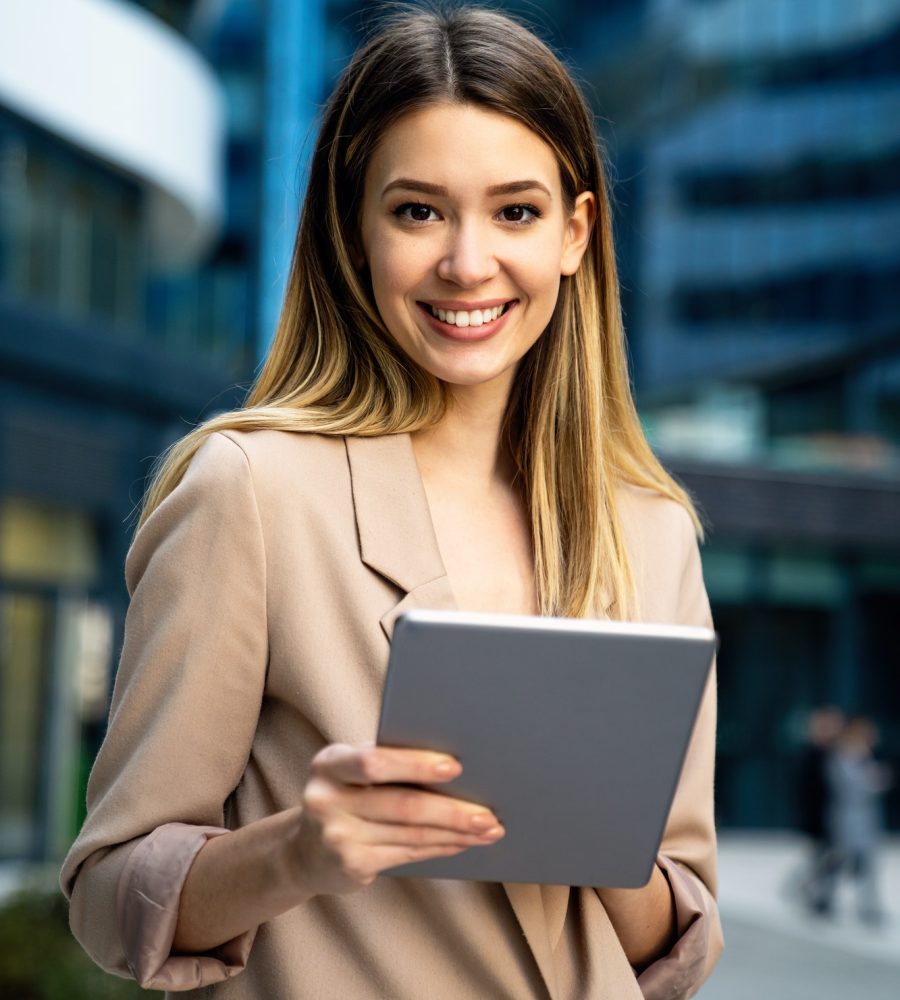 successful-businesswoman-using-a-digital-tablet-while-standing-in-front-of-business-building.jpg